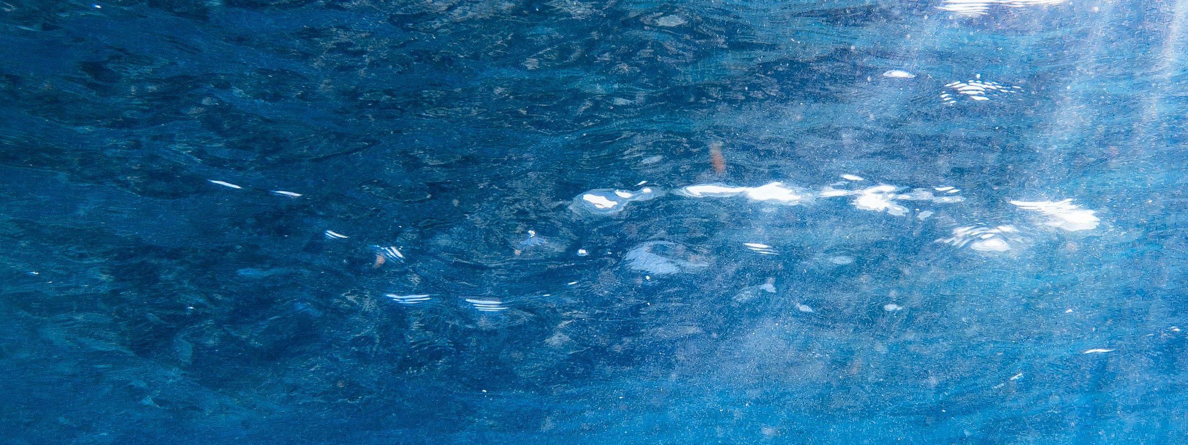 Sunlight streaming through the sea surface onto a rocky seabed. Stock photograph.