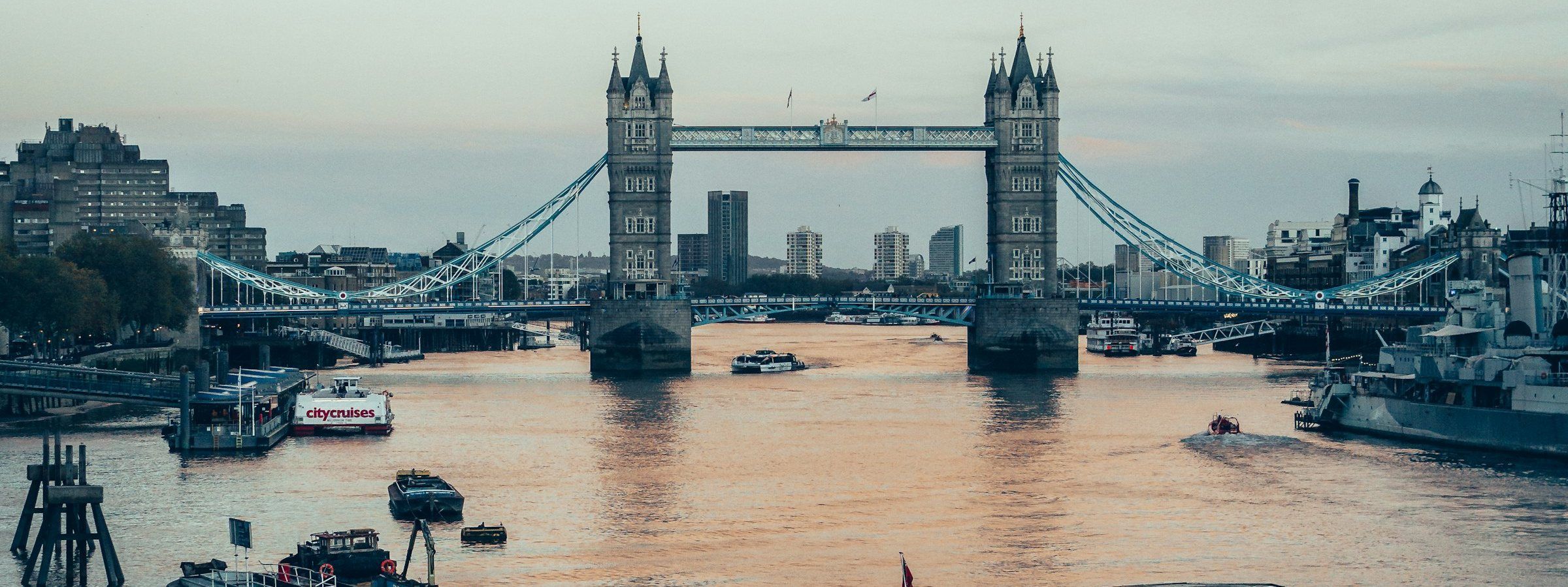 A boat on the tidal Thames beside Tower Bridge, London. Stock photograph.